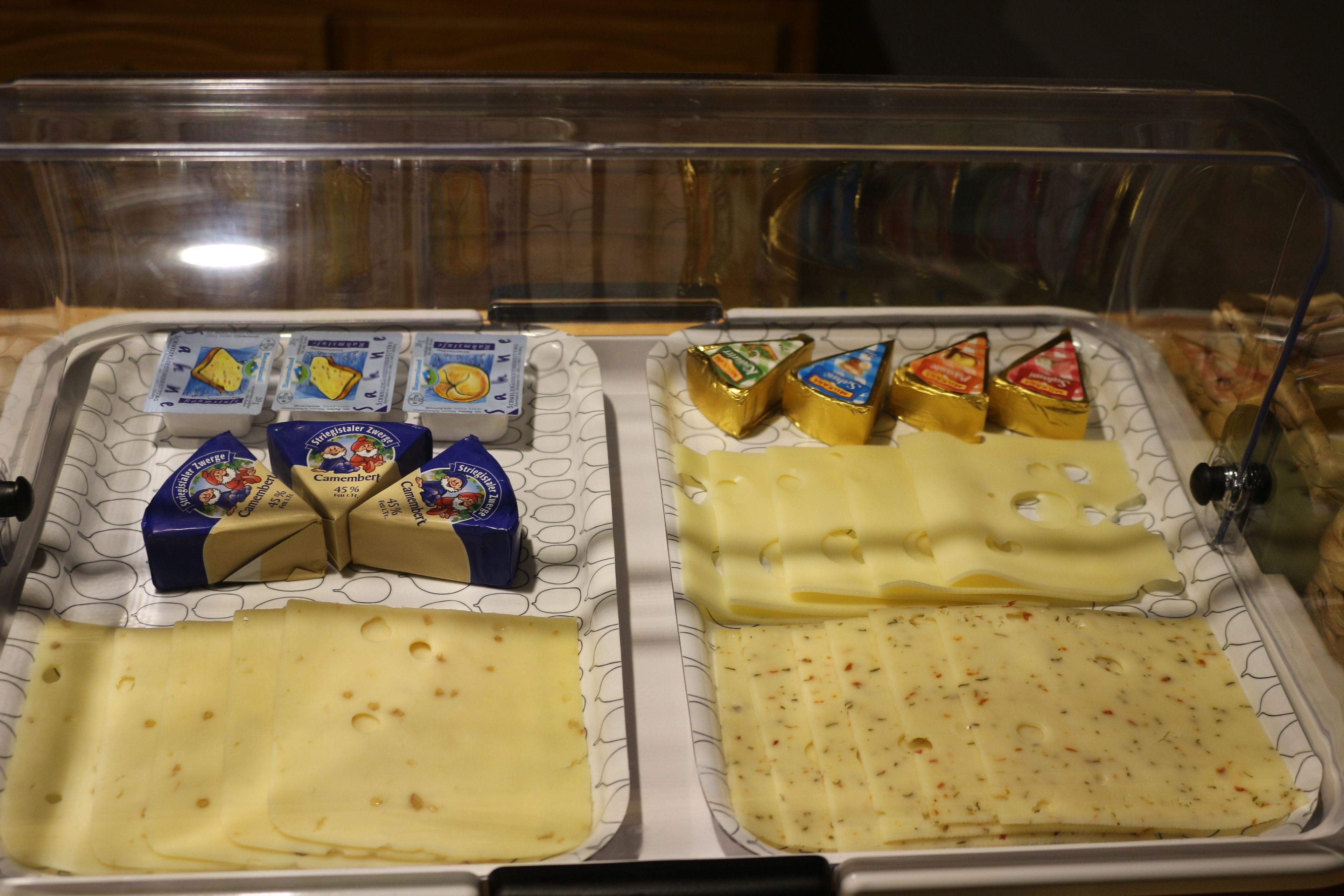 A cheese display with various types of cheese and cheese wheels.