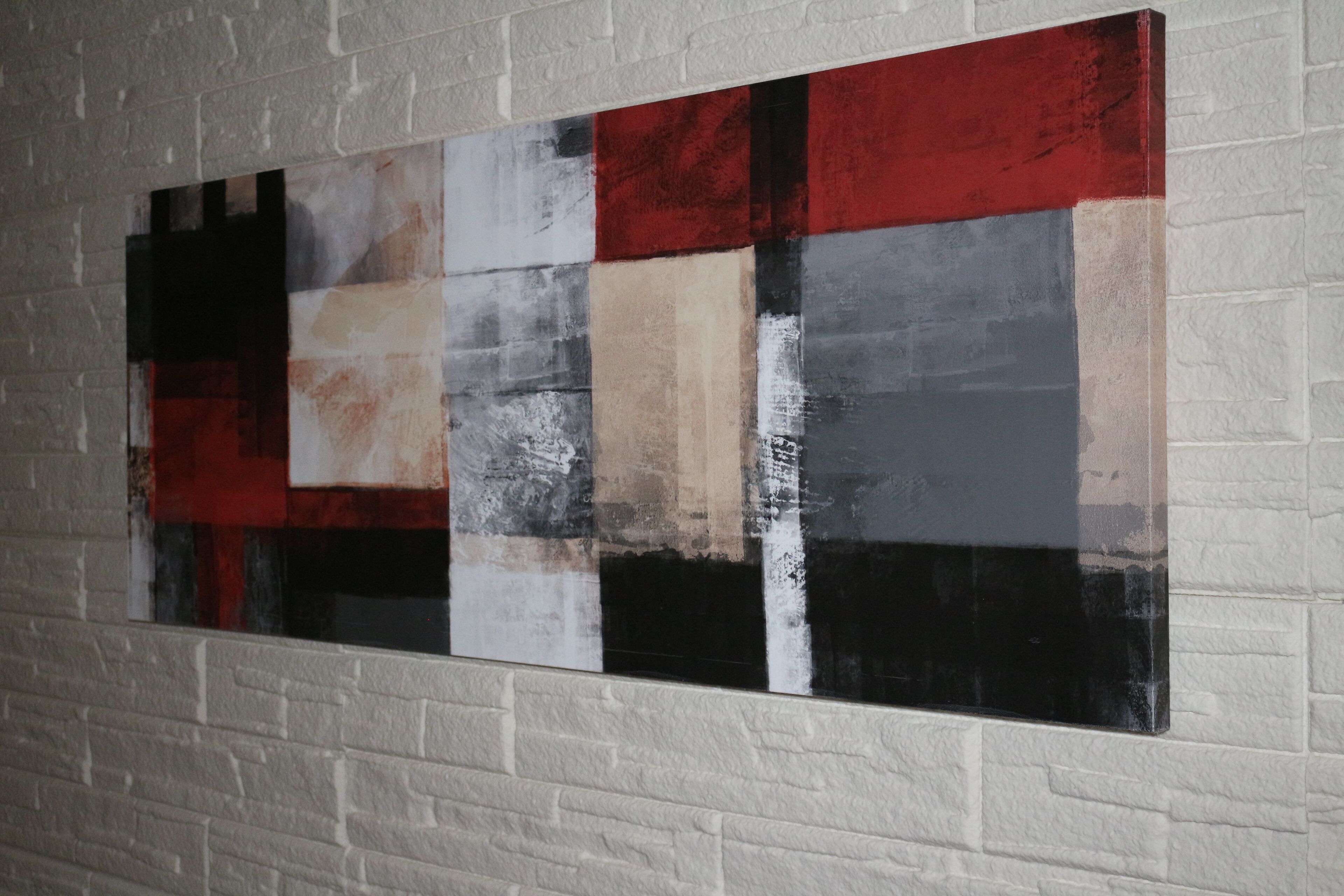 A large abstract painting on a white brick wall.