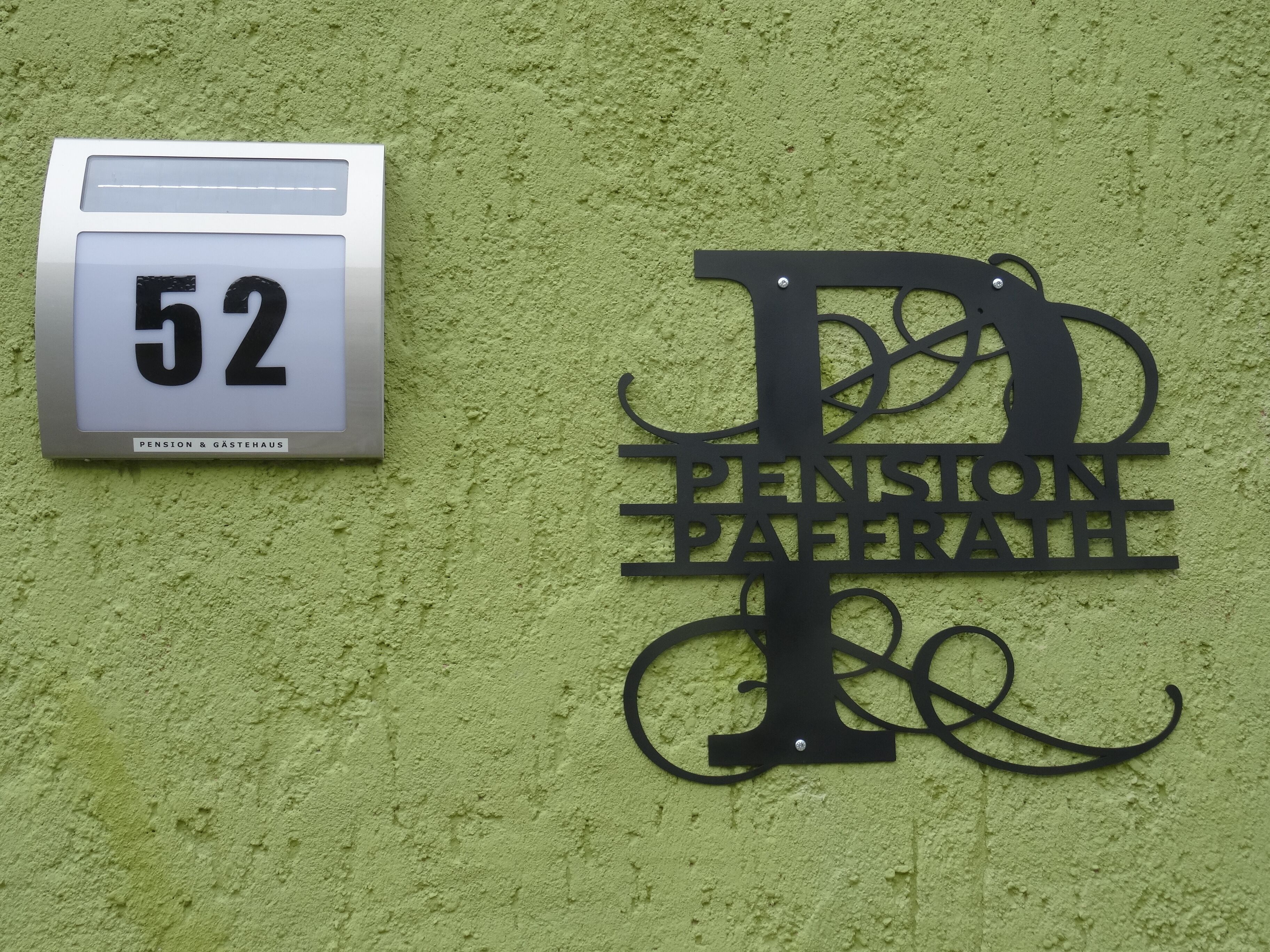 Un letrero de edificio con el número 52 y una placa metálica decorativa que dice "PENSION PAFFERT".