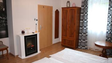 A room with a fireplace, a wooden wardrobe, a round table, and a bed.