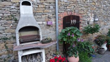 A stone wall with a brick oven, a wooden door, and various potted plants.