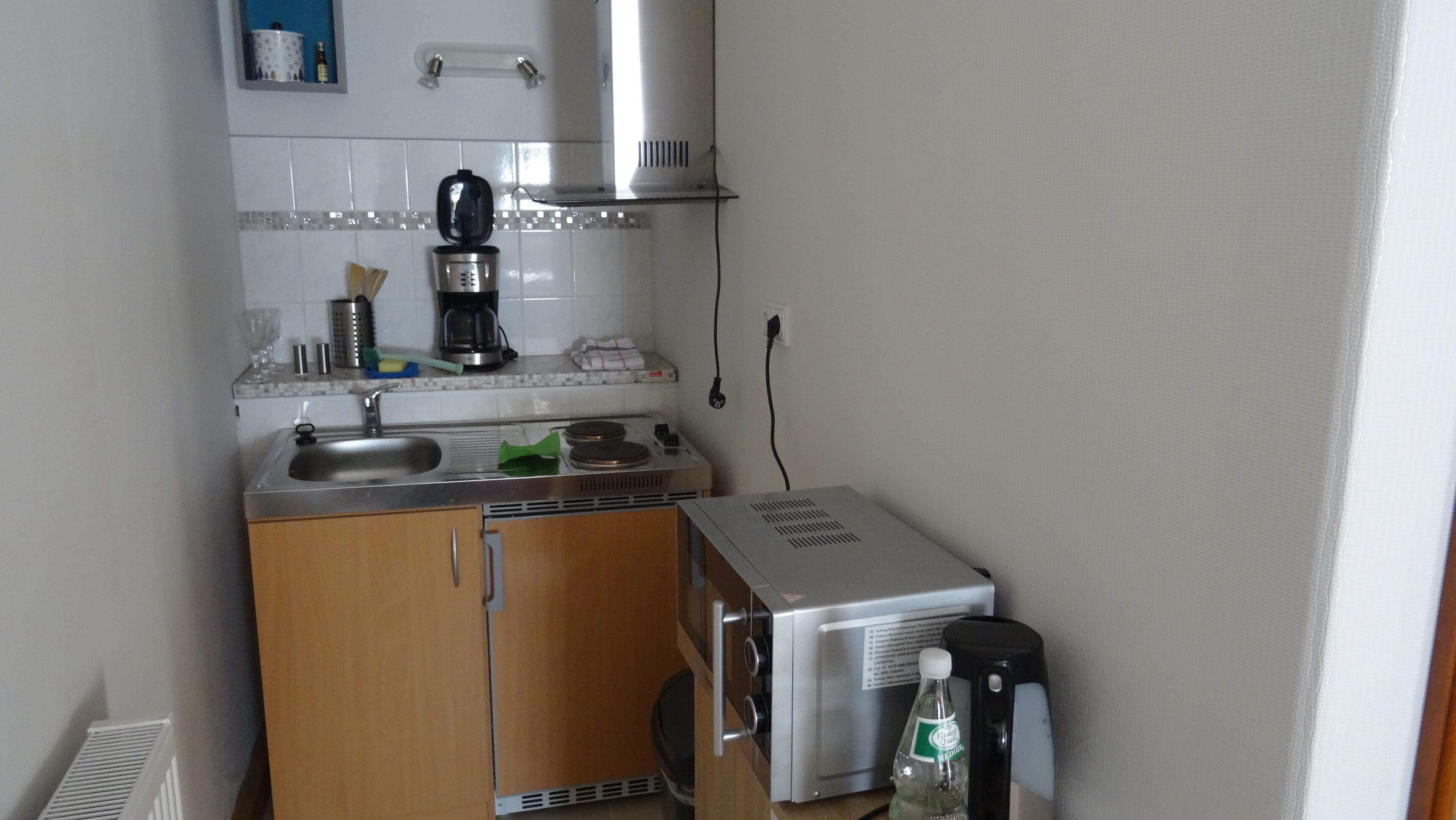 Eine kleine Küche mit Spüle, Herd und Kaffeemaschine.