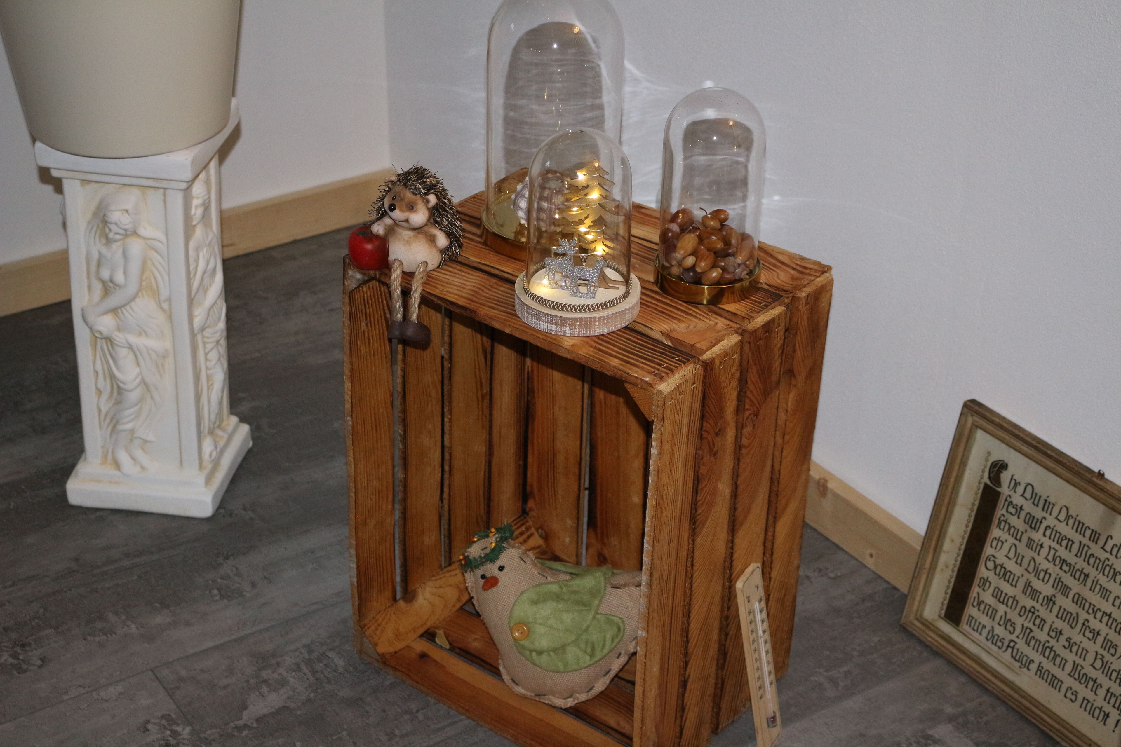 A wooden side table with decorative items including a figurine, a small Christmas tree, and a framed text.