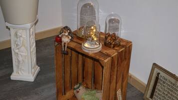 A wooden side table with decorative items including a figurine, a small Christmas tree, and a framed text.
