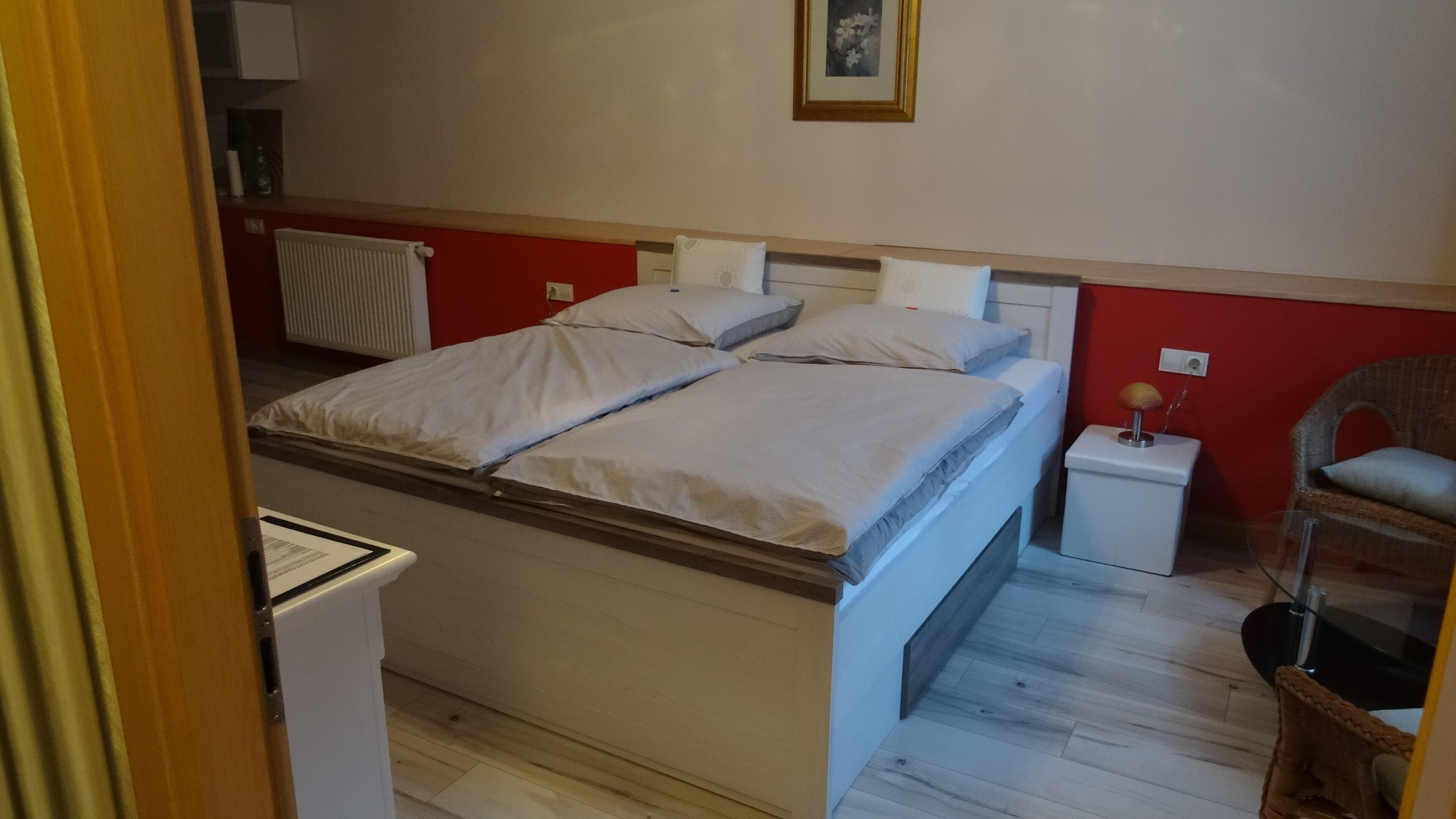Ein Zimmer mit einem Bett, einem Nachttisch, einem Sessel und einer Heizung.