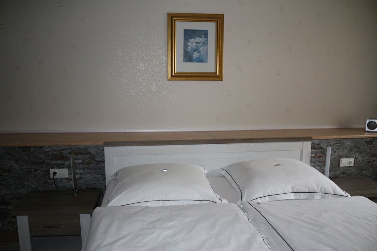 Une chambre à coucher avec un lit, une table de chevet, un tableau accroché au mur et un mur en pierre.