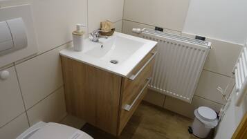 A small bathroom with a toilet, sink, and radiator.