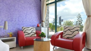 A modern living room with two red leather sofas, a round wooden coffee table, and a large window with a view of the city. - Da Jen Shan Style Resort (Hengchun)
