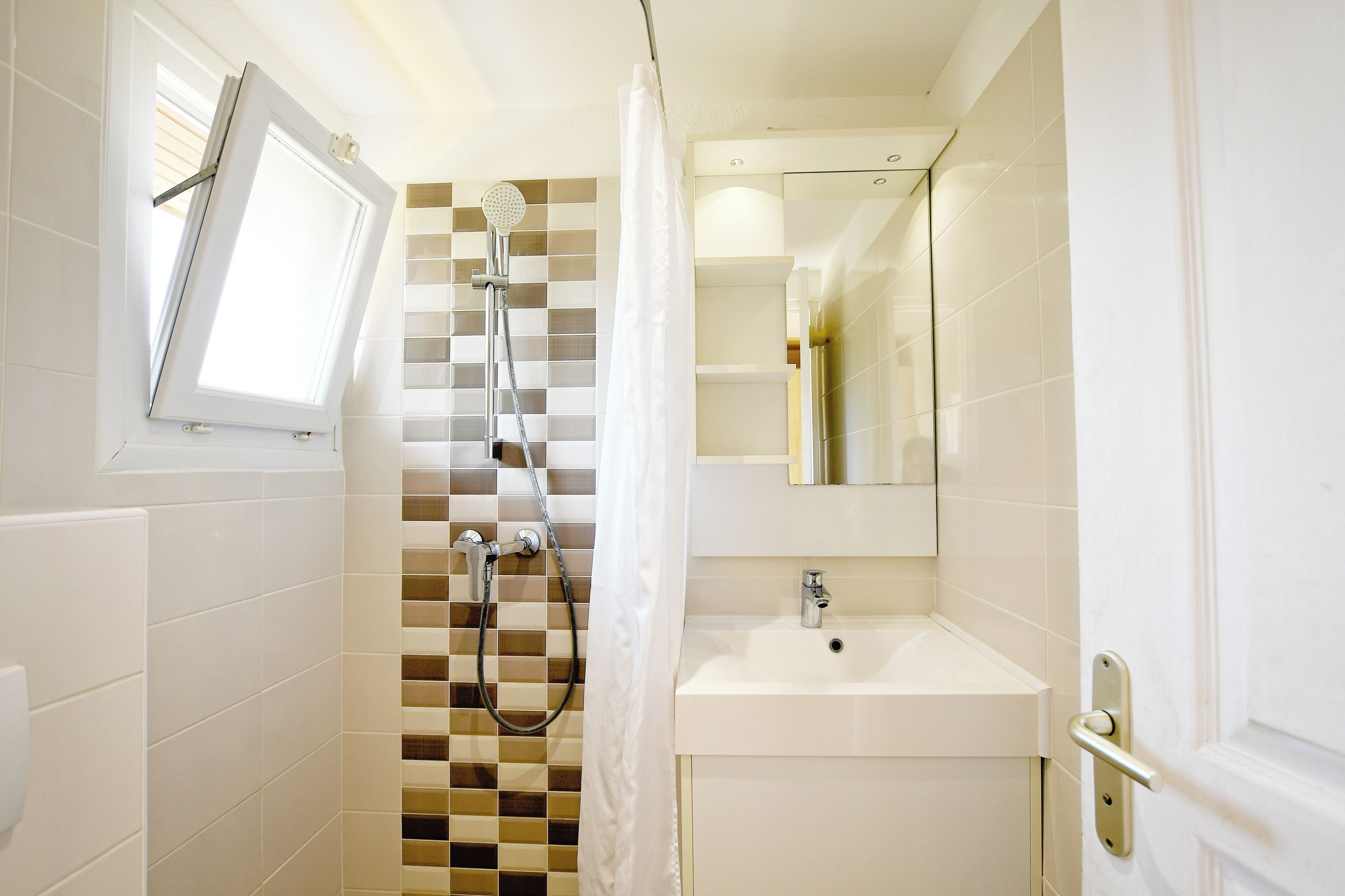 Een moderne badkamer met een douche, een wastafel en een spiegel.