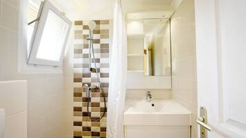 Een moderne badkamer met een douche, een wastafel en een spiegel.