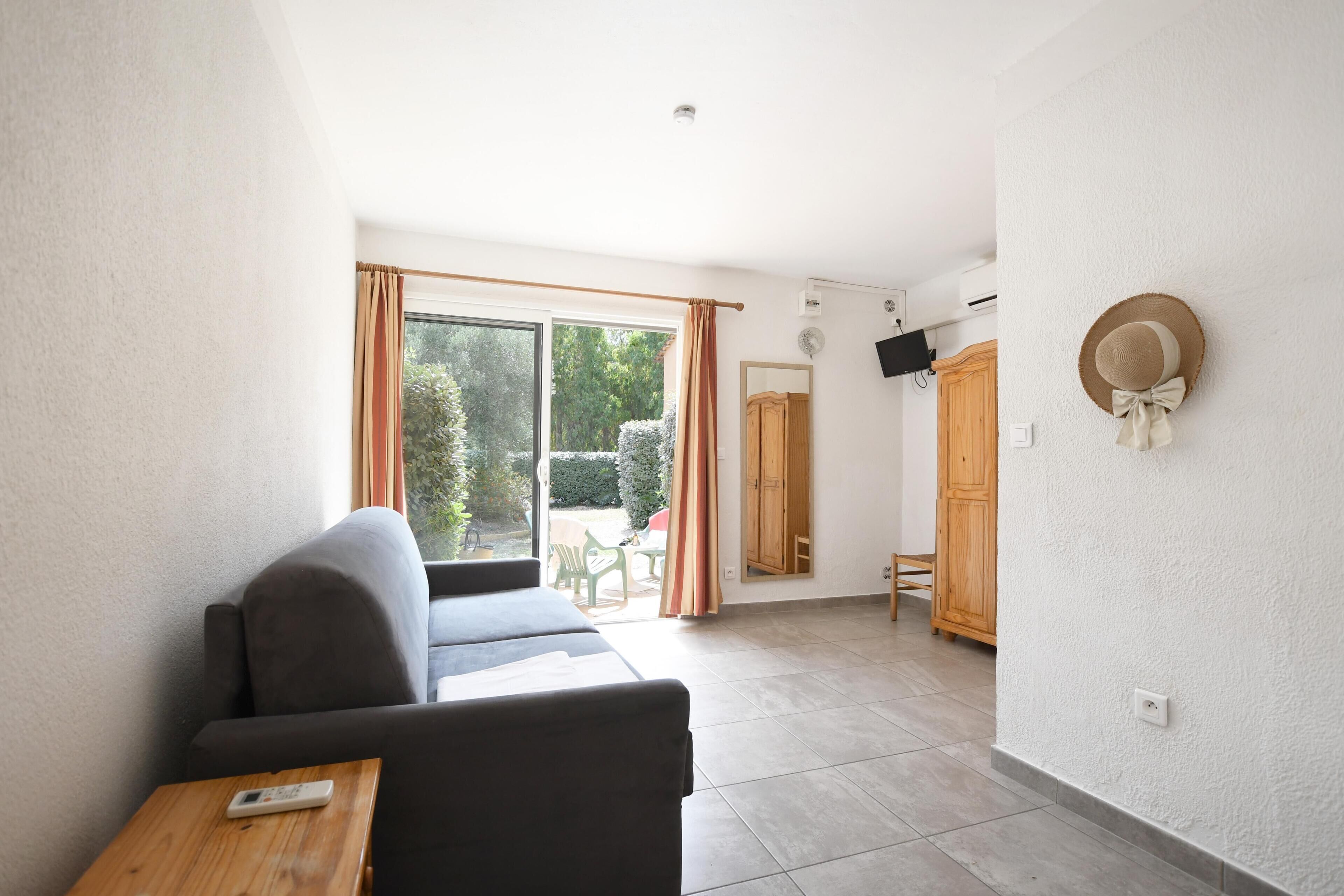 A living room with a sofa, a table, and a sliding glass door leading to an outdoor area.