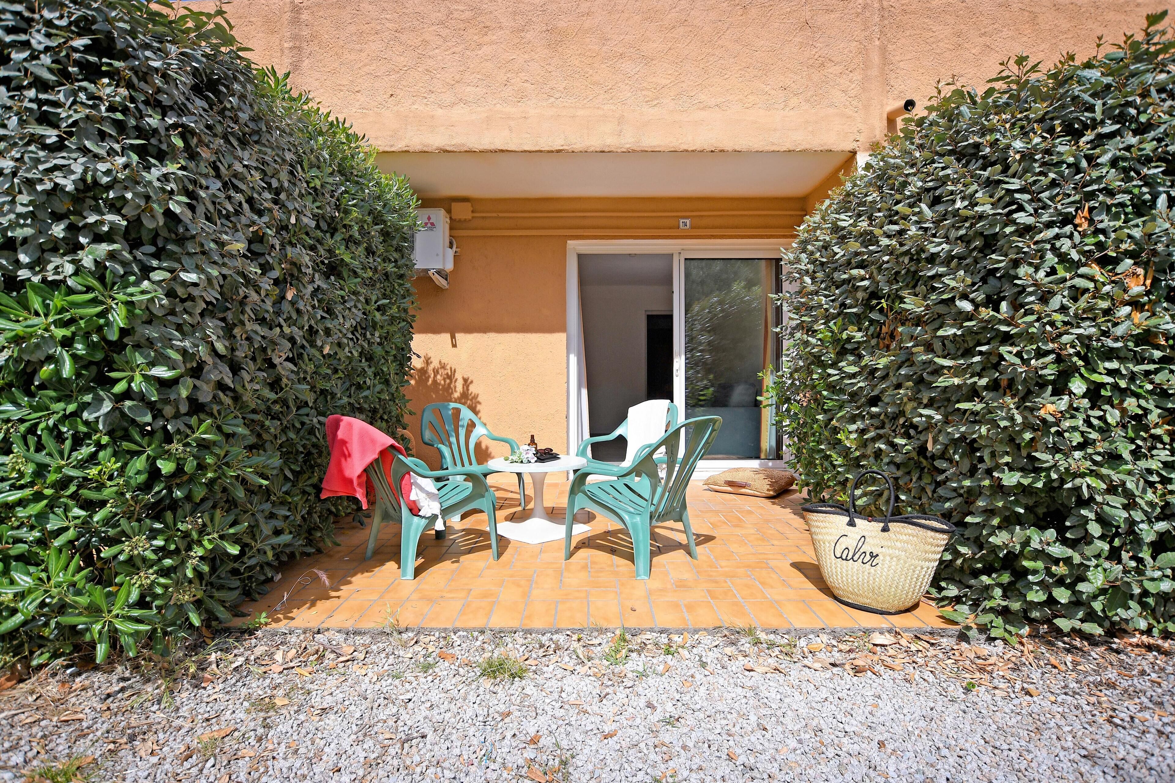 A patio with a table and chairs, a red tablecloth, and a large woven basket.