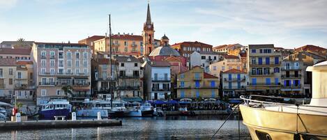 Un puerto con barcos amarrados, una imponente torre de iglesia y edificios coloridos a lo largo de la costa.