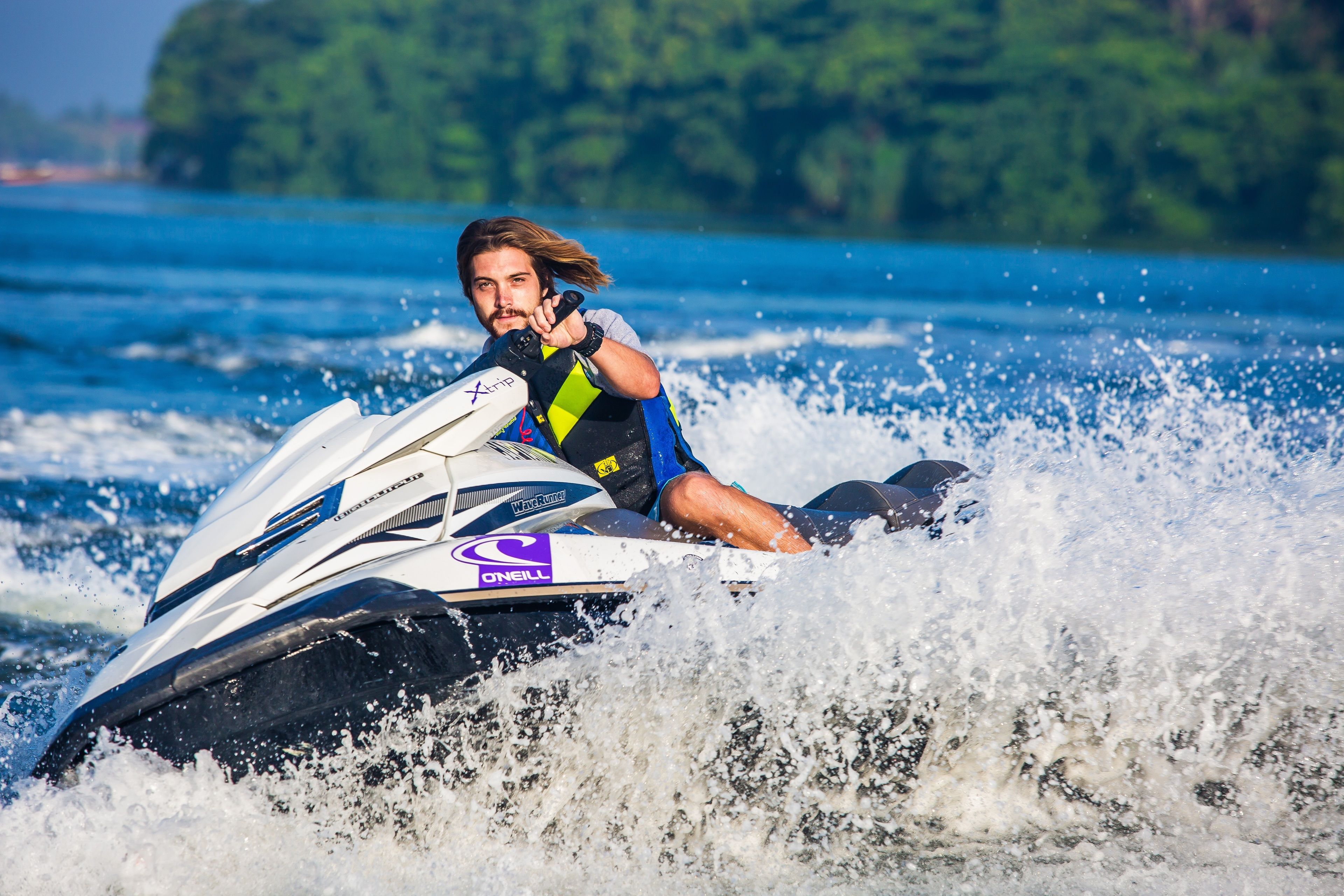 A person jet skiing on a body of water with a forested island in the background.