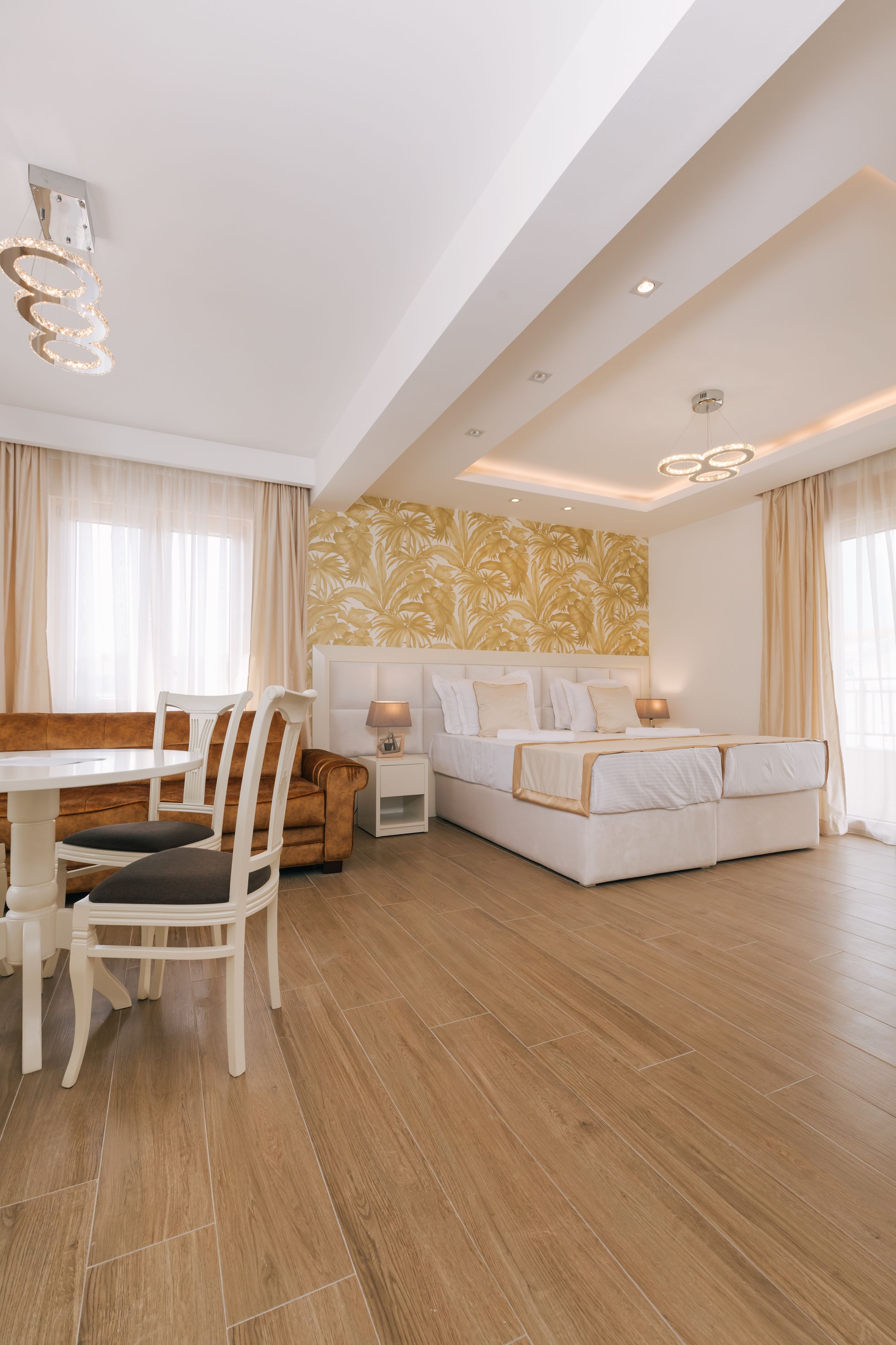 A modern hotel room with a dining area, a sofa bed, and a patterned wall.
