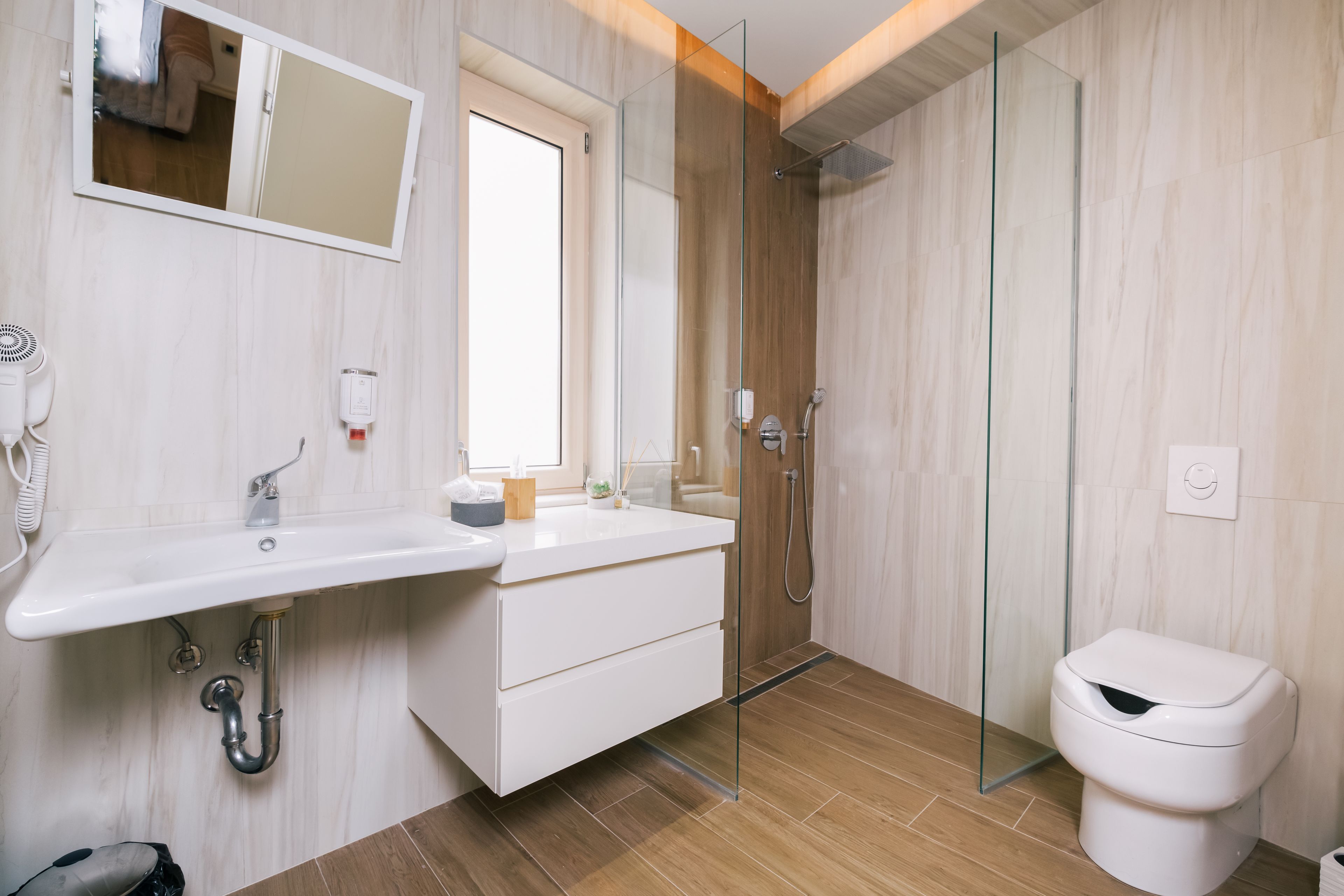 A modern bathroom with a glass shower enclosure, a white sink with a mirror, and a toilet.