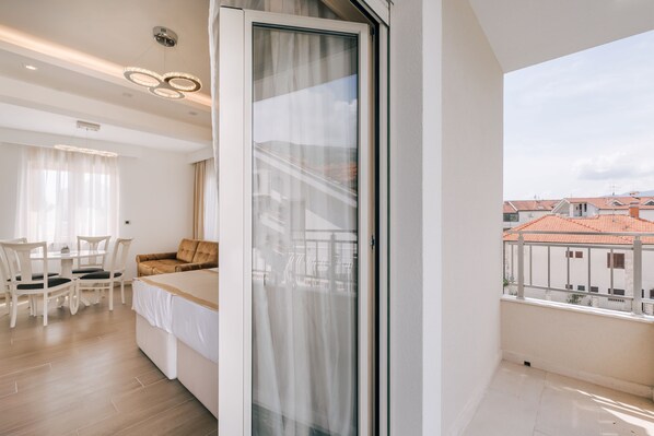 Quarto de hotel moderno com varanda, área de refeições e vista para a paisagem urbana.