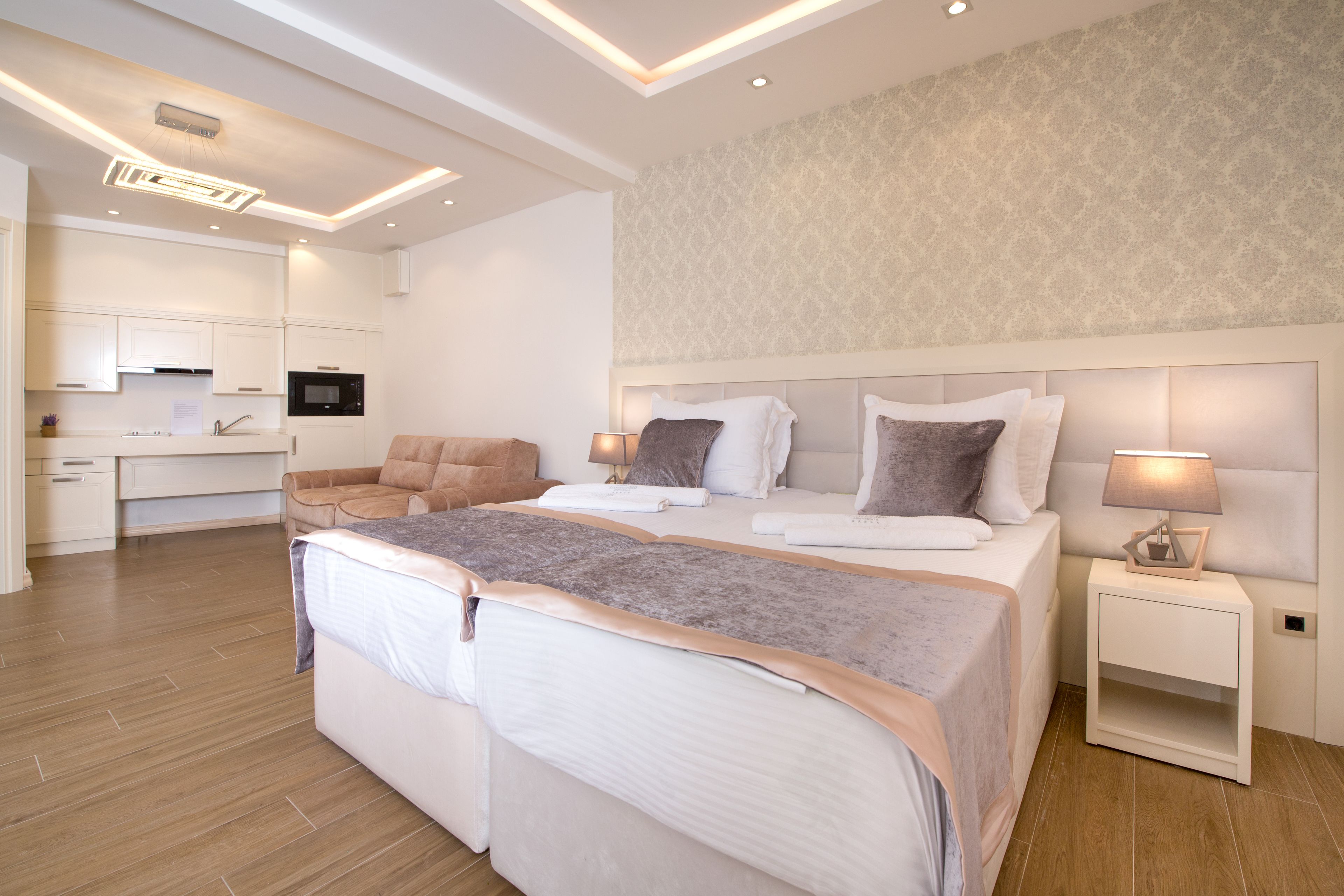 Une chambre moderne avec un grand lit, des tables de chevet, une commode, un bureau et un coin cuisine.