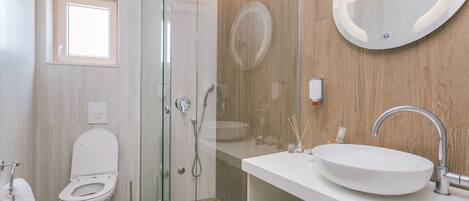 A modern bathroom with a glass-enclosed shower, a white sink, and a large mirror.