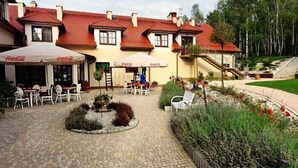 A building with outdoor seating and Coca-Cola branded umbrellas. - Hotel Dudek (Mniów)