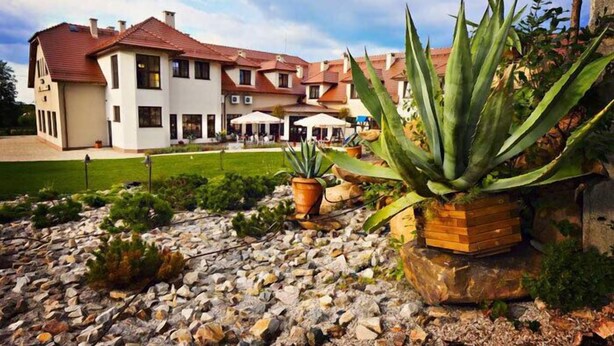 A two-story building with a red-tiled roof, a well-maintained lawn, and potted plants. - Hotel Dudek (Mniów)