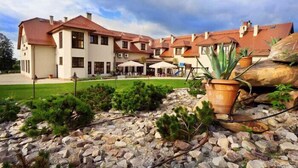 A multi-story hotel with a courtyard, outdoor seating, and potted plants. - Hotel Dudek (Mniów)