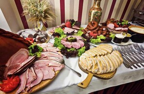A buffet table with various meats, vegetables, and bread.