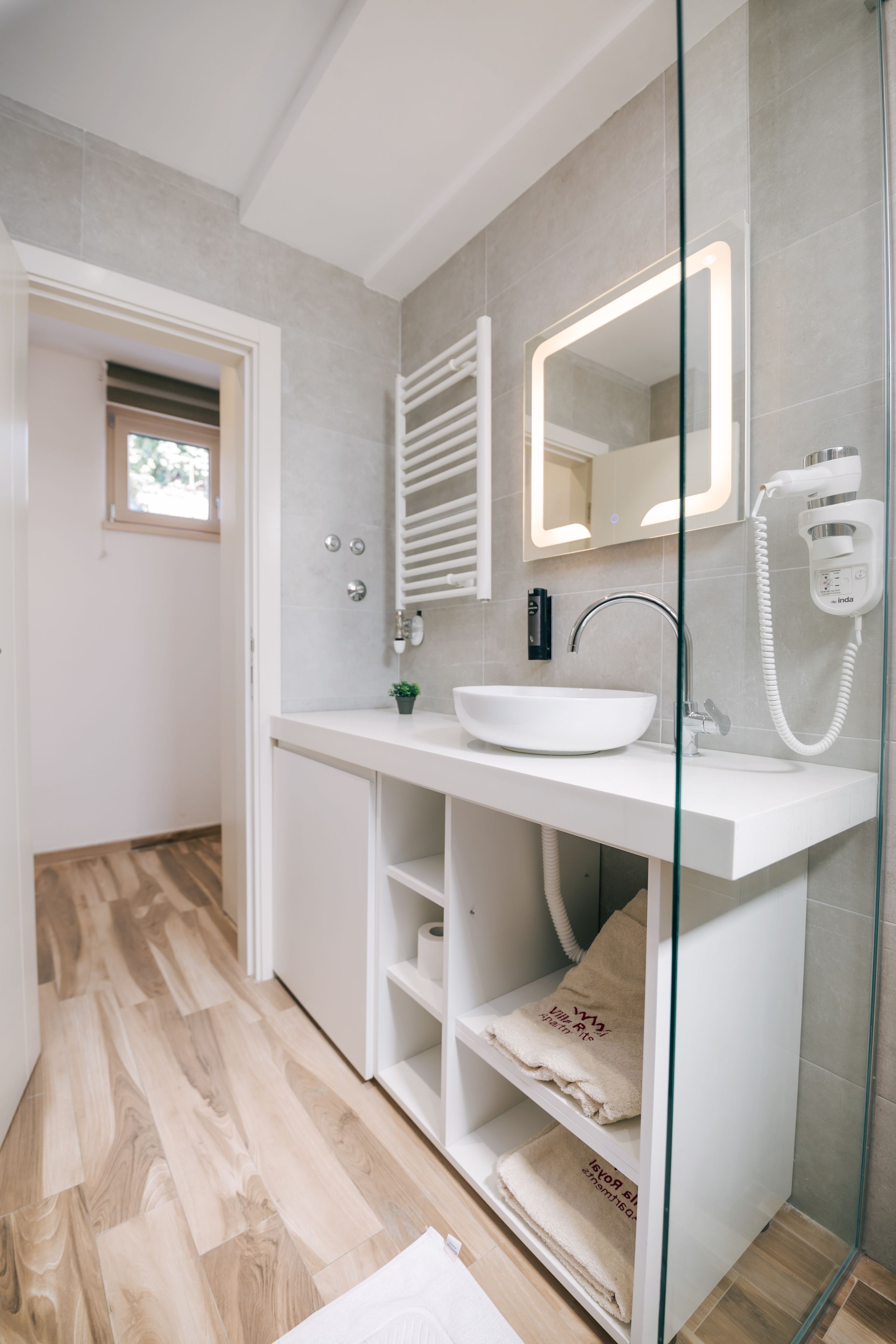 A modern bathroom with a white sink, glass shower enclosure, and a large mirror.