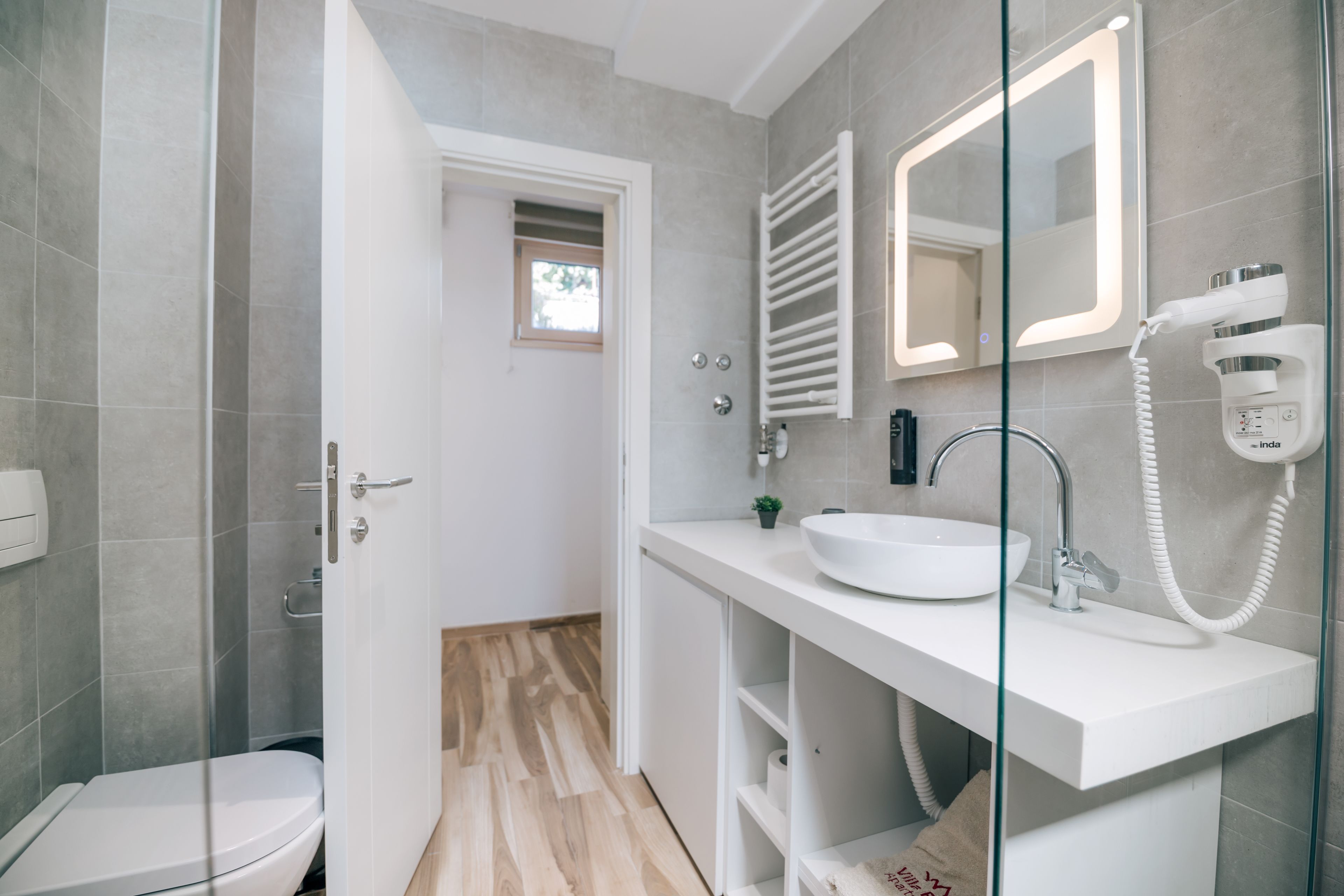 Ein modernes Badezimmer mit einer Duschkabine aus Glas, einem weißen Waschbecken und einer Toilette.