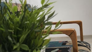 A room with a potted plant, a wooden chair, and two framed artworks on the wall. - Visit Lublin Apartments Piłsudskiego (Lublin)