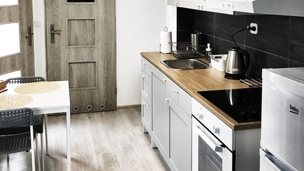 A modern kitchen with wooden cabinets, a stainless steel refrigerator, and a wooden countertop. - Visit Lublin Apartments Piłsudskiego (Lublin)