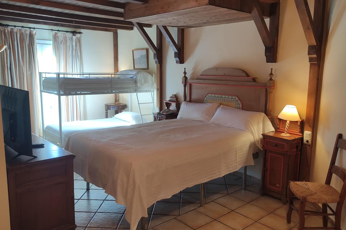 Un dormitorio con una cama grande, un escritorio con computadora, una silla y una mesita de noche con lámpara.