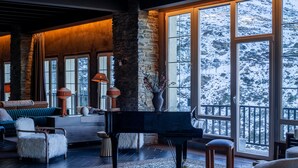 A spacious living room with a grand piano, large windows, and a cozy seating area. - The Mountains Hotel (Monachil)