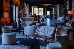 A spacious lobby with leather sofas, armchairs, and a coffee table. There are stone walls and large windows providing natural light. - The Mountains Hotel (Monachil)