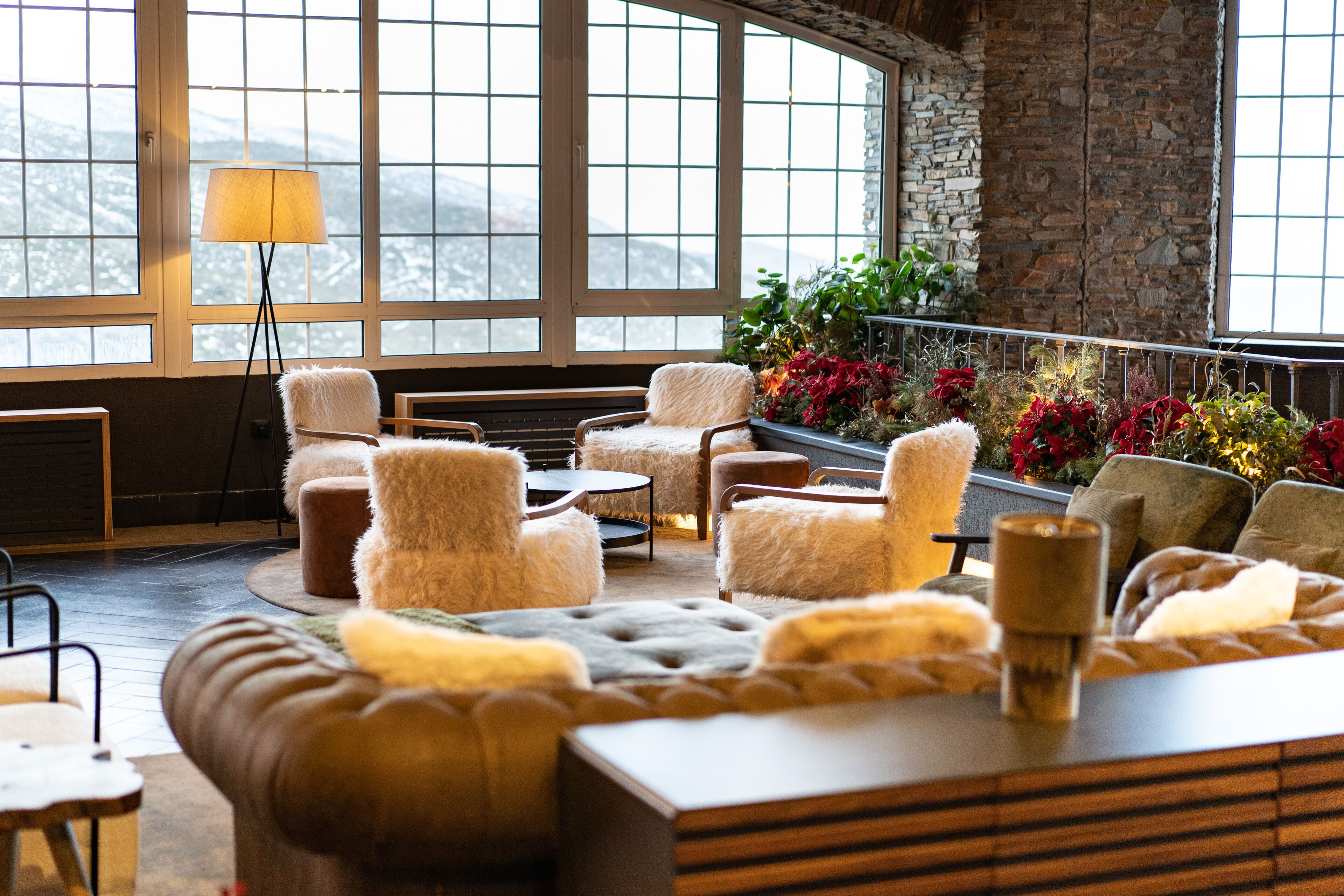 A cozy lounge area with plush seating, a lamp, and a view of mountains through large windows.