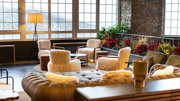 A cozy lounge area with plush seating, a lamp, and a view of mountains through large windows.