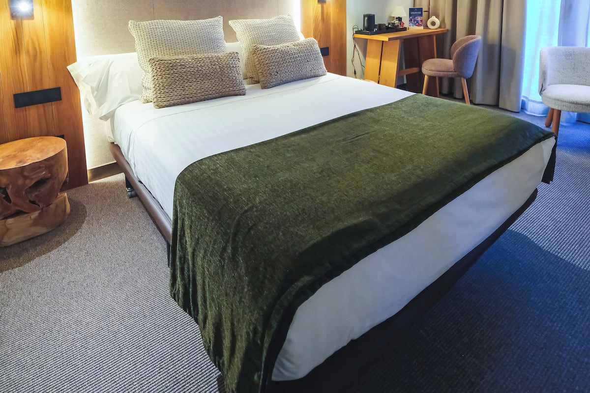 Una habitación de hotel con cama, escritorio, silla y cortinas.
