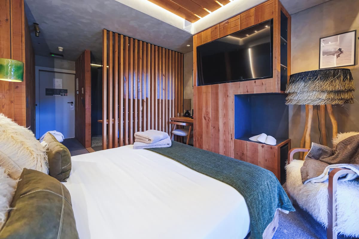 Una habitación de hotel moderna con una cama grande, un escritorio, un televisor y zona de ducha.