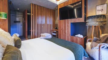 A modern hotel room with a large bed, a desk, a TV, and a shower area.