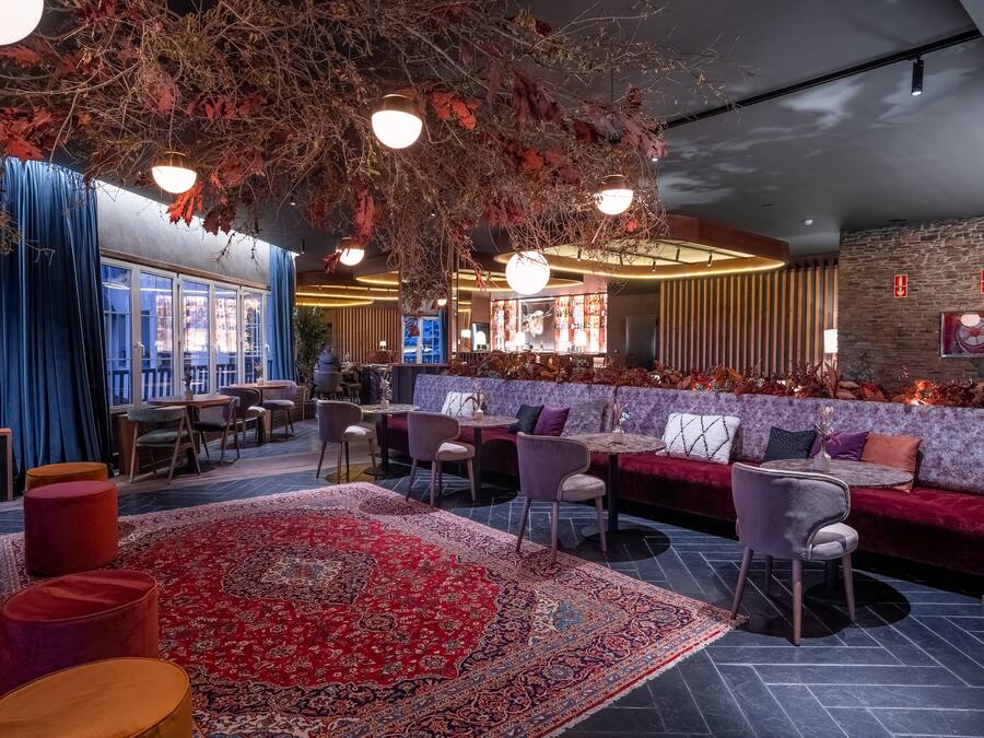 Un interior moderno con una zona de estar, un bar y vistas a la ciudad.