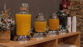 Una estación de bebidas con varios dispensadores de jugo de naranja, una cesta tejida y un florero con flores secas.
