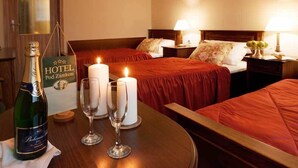 Een hotelkamer met twee bedden, een tafel met champagne en glazen, en een bord met de naam van het hotel.