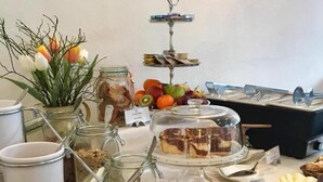 Een buffettafel met diverse gerechten, waaronder fruit, salades en desserts.