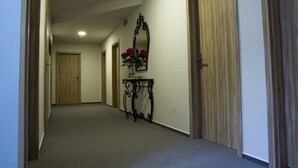 Een gang met houten deuren, een vloerbedekking en een spiegel met bloemen op de muur.