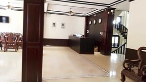 A reception area with a reception desk, a staircase, and wooden furniture. - Singha Hotel (Oudomxay)