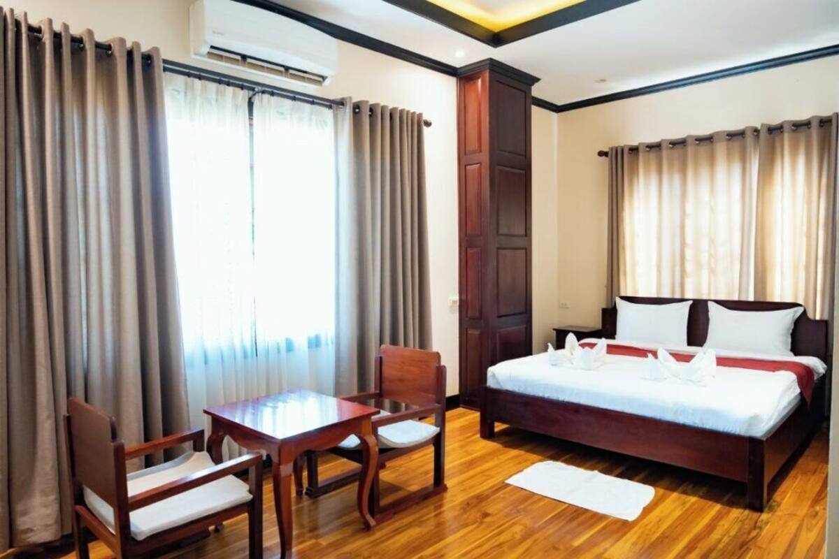 Ein Hotelzimmer mit einem Bett, einem Schreibtisch, zwei Stühlen und Vorhängen.
