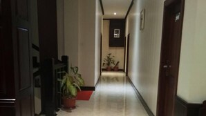 A hallway with a marble floor, wooden doors, and potted plants. - Singha Hotel (Oudomxay)