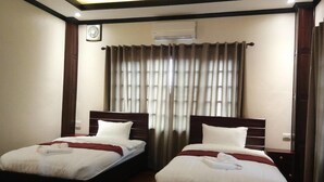 A hotel room with two beds, a ceiling fan, and a window with curtains. - Singha Hotel (Oudomxay)