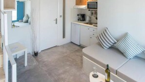 A modern apartment with a loft-style living area, a kitchen, and a staircase leading to an upper level. - Euphoria Suites (Santorini)