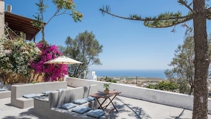 A terrace with a sofa, a small table, and a potted plant. - Euphoria Suites (Santorini)